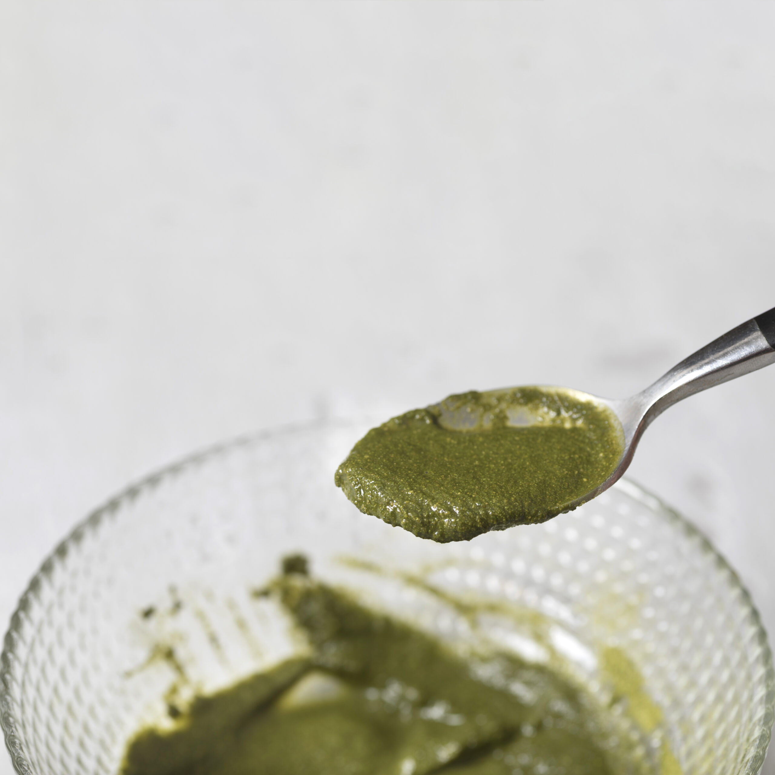 spoon-with-green-sauce-above-bowl-on-table